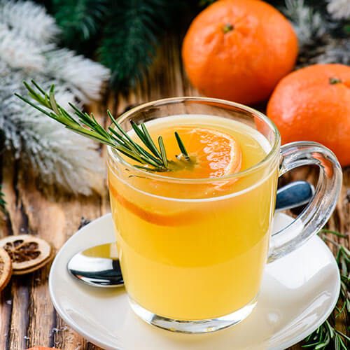 Orange winter punch with a sprig of rosemary in it